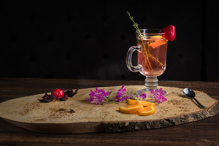 奇利肉桂波旁热腾腾的玻璃杯在木制横断面树干树装饰薄荷，草莓和橙子。 复制菜单空间