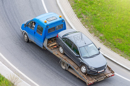 车祸中车轮破碎的客车被装上了一辆疏散卡车，沿着公路行驶，然后转上公路，从空中俯瞰