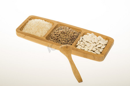 浅灰底色摄影照片_原白芸豆、扁豆和大米在木制的盘子和木勺上隔绝白色的底色, 顶部的景色。宏, 关闭.