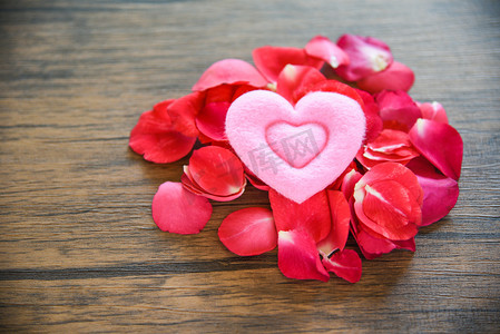 情人节爱心的概念/一堆玫瑰花瓣与粉红色的心装饰在木桌质朴的背景 