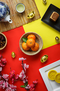 节日会场布置摄影照片_鸟瞰布置装饰的空中形象中国新年和农历节日的背景概念。在办公桌上的现代红黄相间的纸上放上新鲜的橙子和食物和饮料。柔和色调.