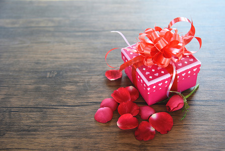 礼品盒粉红色与玫瑰花瓣花浪漫的礼物情人节在木质朴纹理背景顶部视图  