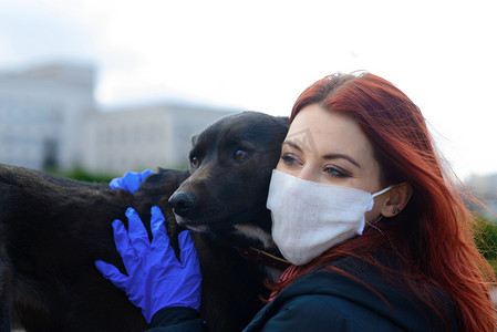 年轻的女性使用面罩作为防止与她的狗一起散步的验尸官。全球COVID-19大流行病概念、动物