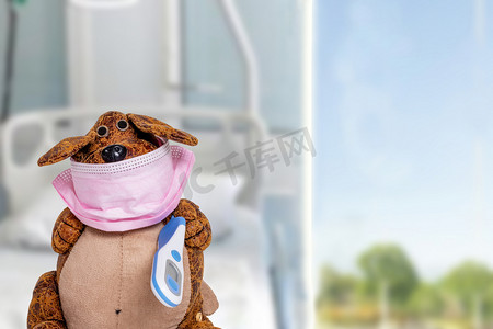 Coronavirus检疫概念一只带着外科口罩和发热温度计的有趣的狗在模糊的医院背景上。待在家里，自我封闭，远离社会.