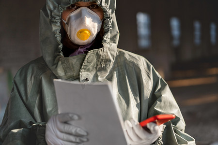 防疫人员海报摄影照片_医生戴着防护面罩抵御考拉韦。工作人员预防装备。手拿着海报待在家里