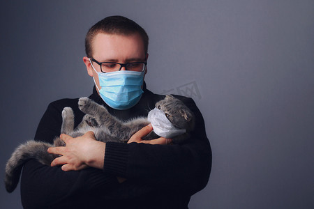 猫和人摄影照片_苏格兰人的猫和人戴着口罩繁殖后代.covid-19大流行病（Coronavirus感染）的概念和检疫。三.经验的交流