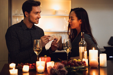 美丽的激情夫妇有一个浪漫的烛光晚餐在家里, 男人提出建议