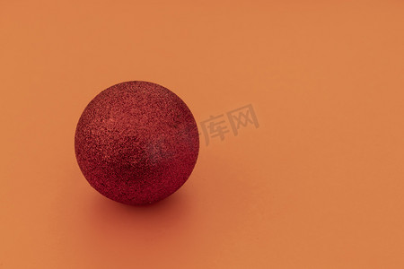 红色圣诞装饰球在橙色背景的左侧。右边的复制空间