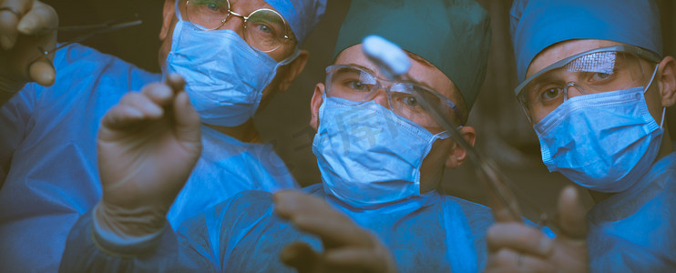 在手术室工作的外科医生小组用蓝色色调。医疗团队执行操作