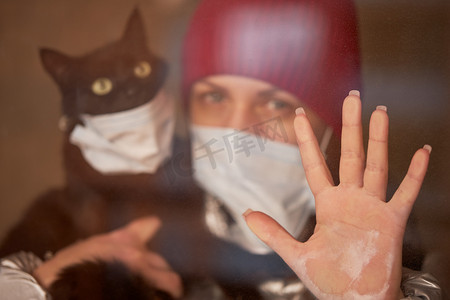 一个戴着防护面具的年轻女子怀里抱着一只蒙面猫。有意识的公民，在与大头牛流行病的斗争中