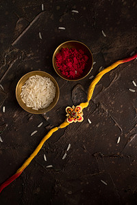 Raksha Bandhan背景，有优雅的Rakhi 、 Rice Grains和Kumkum 。 手镯印度传统的腕带，是兄弟姐妹间爱情的象征.