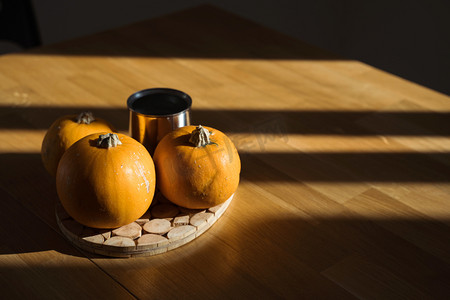 南瓜装饰在家中的木制桌子上晒太阳.秋日的余晖.万圣节 