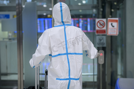 一名亚洲男子在机场电梯、安全旅行、鱼子酱保护、社会疏离等方面都穿着ppe西服 .