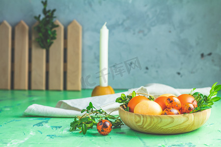 复活节贺卡与彩色黄色橙色鸡蛋与鹌鹑蛋和绿色树枝在木板在绿色混凝土表面背景。复制空间。色调的图像