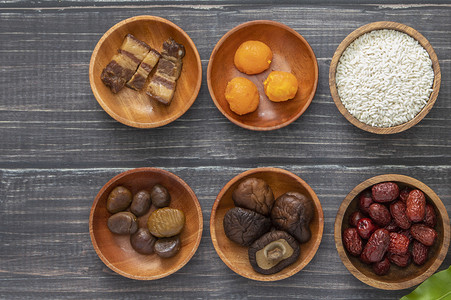dried摄影照片_Bowls with dried fruits and white rice on a wooden surface.