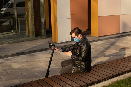 戴着防护面罩的男人，用智能手机和电动车对抗考拉威斯。Coronavirus男人面具