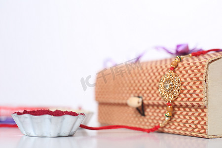 rice摄影照片_印度节：Raksha Bandhan背景，有优雅的Rakhi 、 Rice Grains和Kumkum 。手镯印度传统的腕带，是兄弟姐妹间爱情的象征.