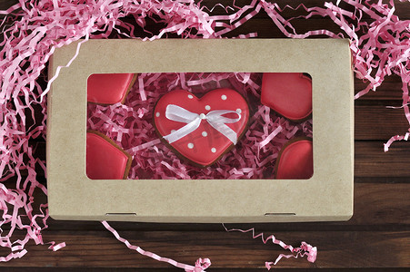 情人节的玻璃心形饼干- -美味的自制天然有机糕点，充满爱的情人节烘焙，爱的概念（红色和粉色心形蛋糕和木制背景的心形棒棒糖） 。 礼品包装)