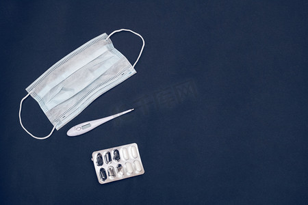 Medical face masks, thermometer and tablets on gray background