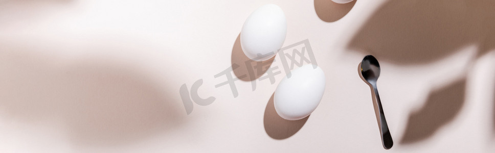 顶部的白色煮熟的鸡蛋和茶匙在灰色桌子上的阴影，网站标题