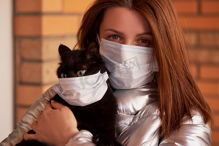 一个戴着防护面具的年轻女子怀里抱着一只蒙面猫。有意识的公民，在与大头牛流行病的斗争中