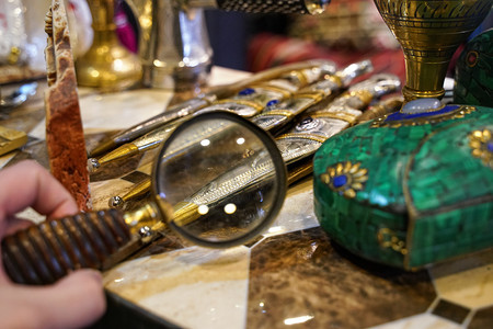 在古董店用放大镜检查传统匕首的细节，并对细节进行总结
