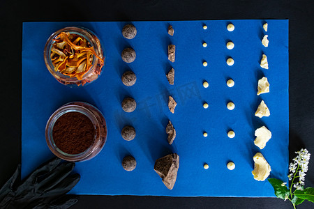深色和白色的巧克力、可可豆和糖橙被放在蓝色的背景上。在家里做健康美味的无糖糖果的配料。俯瞰，特写.