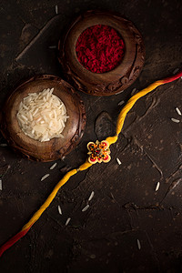 Raksha Bandhan背景，有优雅的Rakhi 、 Rice Grains和Kumkum 。 手镯印度传统的腕带，是兄弟姐妹间爱情的象征.