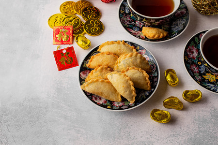中国新年红包摄影照片_装饰品、红包和硬币上的中国符号意味着财富。 茶具与深油炸泡袋，Yau gok 。 农历新年期间的传统小吃.