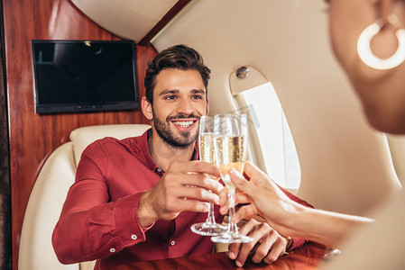 在私人飞机上，笑着的男友和女友与香槟酒杯叮当作响 