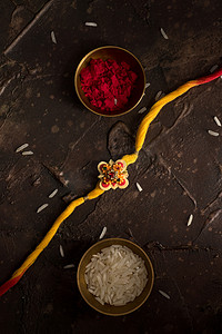 Raksha Bandhan背景，有优雅的Rakhi 、 Rice Grains和Kumkum 。 手镯印度传统的腕带，是兄弟姐妹间爱情的象征.