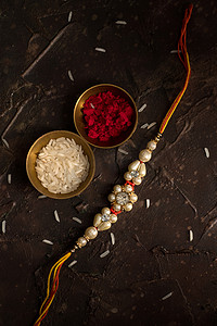 Raksha Bandhan背景，有优雅的Rakhi 、 Rice Grains和Kumkum 。 手镯印度传统的腕带，是兄弟姐妹间爱情的象征.