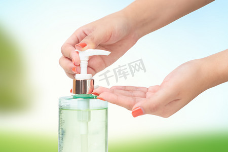 位访客摄影照片_手部使用洗手手部清洁剂凝胶泵分配器模糊的绿色自然背景.