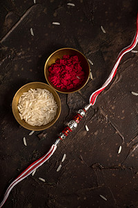 Raksha Bandhan背景，有优雅的Rakhi 、 Rice Grains和Kumkum 。 手镯印度传统的腕带，是兄弟姐妹间爱情的象征.