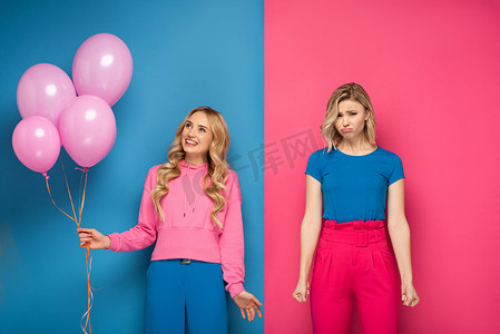 带着气球的金发女孩在忧伤的姐姐身边笑着，背景是蓝色和粉色的