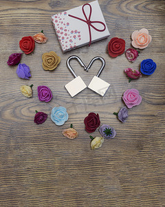 情人节的象征。两个锁形成心形, 礼品盒和玫瑰在木桌顶视图.