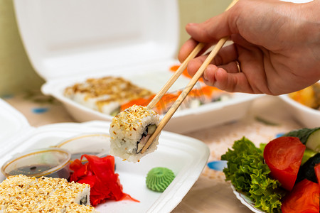 饭桌摄影照片_寿司和带着家庭送餐的面包卷，在饭桌边吃