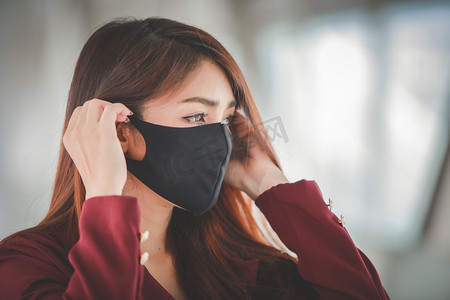 保护妇女摄影照片_亚洲妇女戴口罩保护pm2.5，并在公众场合咳嗽感染Covid-19病毒.