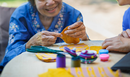 Elderly woman with caregiver in the needle crafts occupational therapy for Alzheimers or dementia