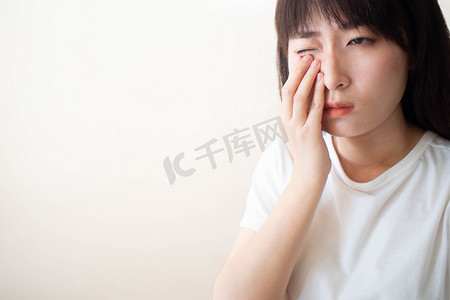 亚洲女人的眼睛感到疼痛，眼睛里感觉到了什么。疼痛的原因包括隐形眼镜问题、结膜炎、异物、干眼症或过敏.