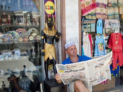 摊位摄影照片_埃及。欧洲人假装坐在该网站商户摊位上看埃及报纸.