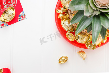 战俘摄影照片_中国新年和战俘概念。顶部查看菠萝与组金锭在红托盘上的白色木桌上. 在锭意味着富裕.