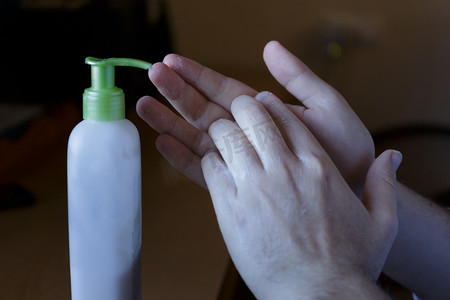 饮水机摄影照片_用饮水机在奶油罐损坏的手上涂抹润肤霜