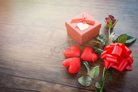老箱子摄影照片_情人节礼品盒红色在木头背景/浪漫的红色心脏情人节红色玫瑰花和礼物箱子丝带弓在老木头-爱概念顶视图拷贝空间
