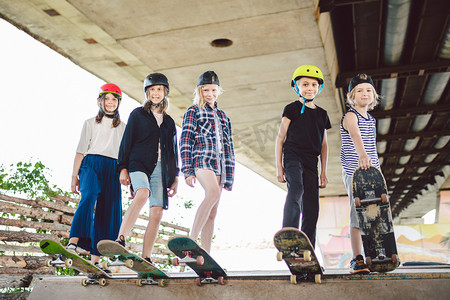 城市里的极限运动儿童滑板俱乐部。一群朋友在滑雪场的斜坡上摆姿势.早期的青春期在滑冰训练中。朋友们在街上的滑板上滑行滑板.