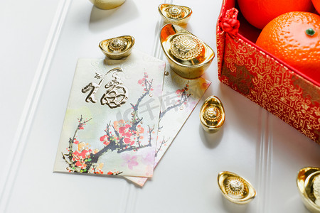 农历新年, 红包包 (昂战俘) 和红色毡织物袋与黄金锭和桔子和花在白色的木桌面上, 中国语言意味着幸福和钢锭意味着富裕.