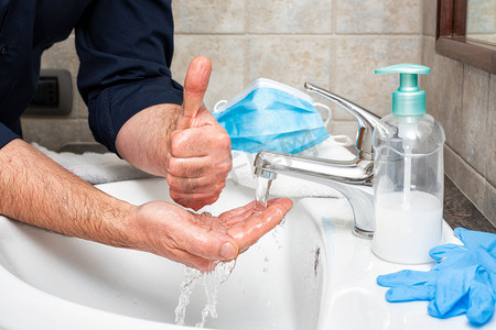 验尸官的预防用热肥皂水洗手可以阻止Covid-19的感染，可以用大拇指向上签名。个人卫生。健康.