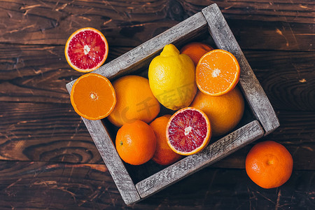 乡背景摄影照片_多汁的整个柠檬，橙子和柚子，新鲜切一半的乡土木背景。顶部视图