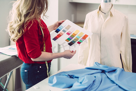 裁缝测量摄影照片_量身定制的妇女选择颜色从调色板的新衬衫在工作室