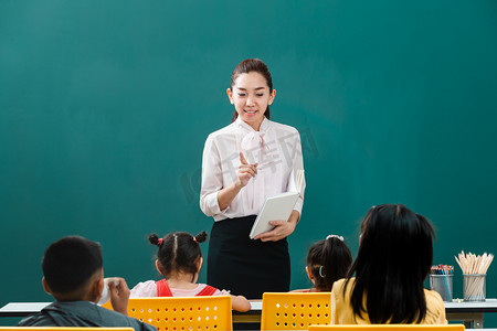 在课堂上, 亚洲老师站在全班同学面前教学生, 学生们自觉地听她说话.